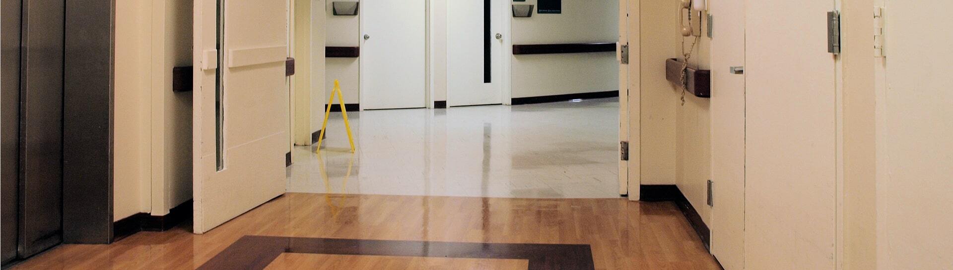Hospital hallway with polished floors and open doors.